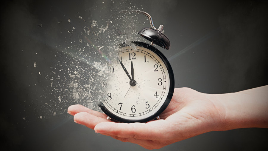 Concept of passing away, the clock breaks down into pieces. Hand holding analog clock with dispersion effect